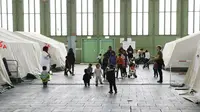 Anak-anak bermain di dekat tenda yang didirikan bagi para migran di dalam hanggar bekas bandara Tempelhof di Berlin, Jerman, Rabu (9/12/2015). Jerman menerima satu juta migran dari beberapa negara yang sedang dilanda perang. (REUTERS/Fabrizio Bensch)
