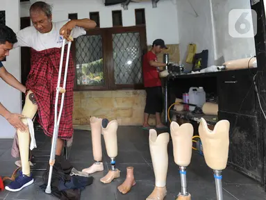 Ortotis prostetis atau pembuat kaki tangan palsu memasangkan kaki palsu buatannya kepada penyandang disabilitas di sebuah bengkel kawasan Ciputat Baru, Tangerang Selatan, Banten, Senin (14/10/2019). Kaki dan tangan palsu dijual dengan harga Rp 5 juta hingga Rp 50 juta. (merdeka.com/Arie Basuki)