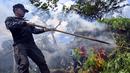Seorang anggota Badan Narkotika Nasional (BNN) membakar tanaman ganja saat penggerebekan pada jalur hutan di Lamteuba, Provinsi Aceh, 18 Mei 2022. (CHAIDEER MAHYUDDIN/AFP)