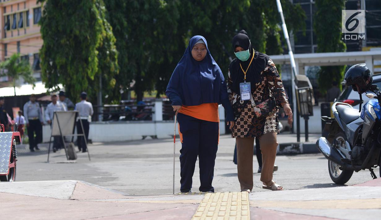 Penyandang disabilitas netra berjalan menyusuri ubin pemandu saat kampanye kegunaan ubin pemandu di trotoar kawasan Rawamangun, Jakarta, Selasa (2/4/2019). Kegiatan tersebut digelar untuk memberikan pengetahuan tentang cara berjalan menggunakan ubin pemandu. (merdeka.com/Imam Buhori)