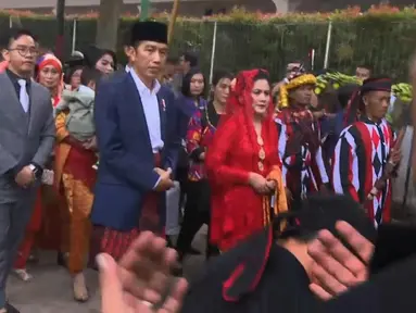 Presiden Joko Widodo dan Ibu Negara Iriana berjalan saat mengikuti  prosesi penyambutan keluarga mempelai wanita secara adat di Bukit Hijau Regency Taman Setia Budi (BHR Tasbi), Medan, Sabtu (25/11). (Liputan6.com/Vidio)
