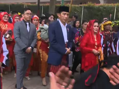 Presiden Joko Widodo dan Ibu Negara Iriana berjalan saat mengikuti  prosesi penyambutan keluarga mempelai wanita secara adat di Bukit Hijau Regency Taman Setia Budi (BHR Tasbi), Medan, Sabtu (25/11). (Liputan6.com/Vidio)