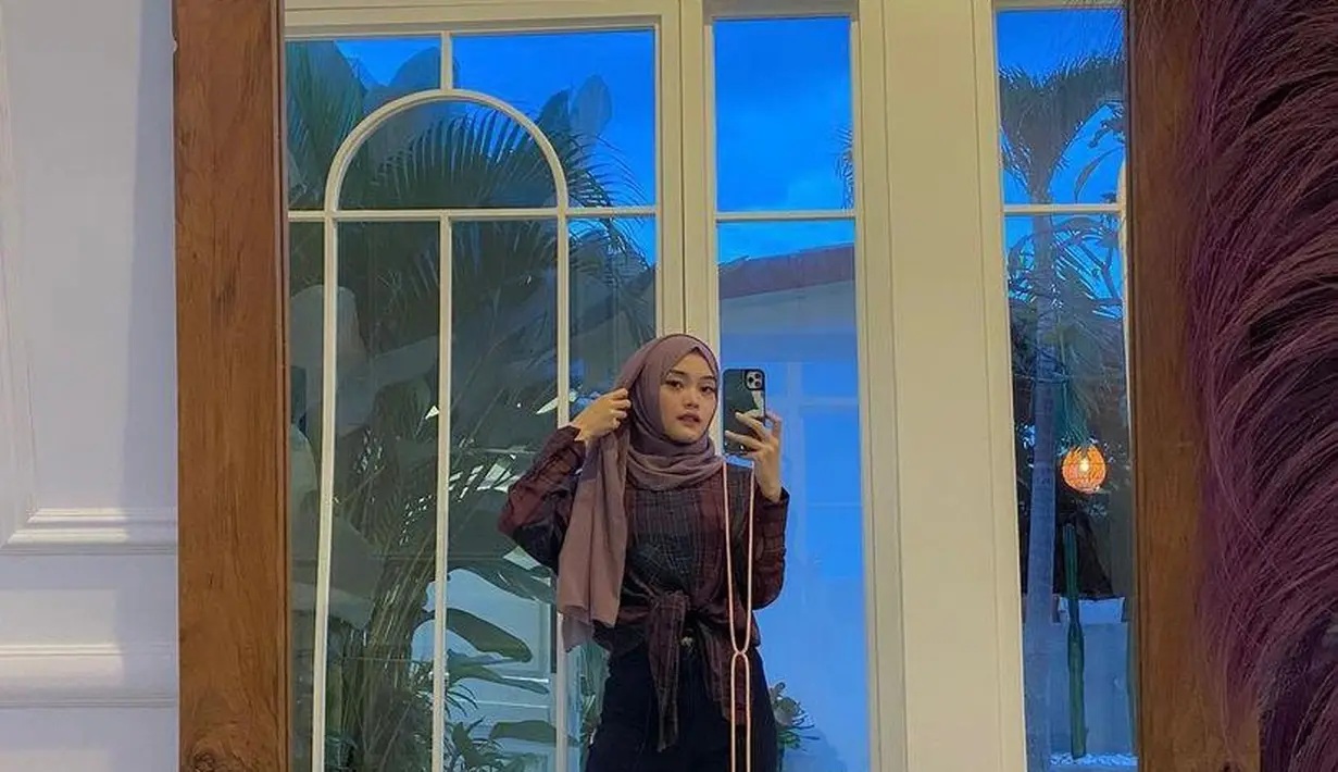 <p>Cocok untuk hangout ke café, gaya anak komedian Sule satu ini bisa jadi inspirasi. Padukan kemeja bermotif dengan celana jeans hitam dan pashmina. Biar makin kece, coba ikat bagian depan kemeja kamu. (Instagram/putridelinaa).</p>