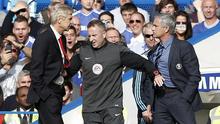 Seorang ofisial pertandingan (tengah) harus memisahkan manajer Arsenal Arsene Wenger (kiri) dan Jose Mourinho (kanan) yang terlibat friksi pada 2014. (AFP/Adrian Dennis)