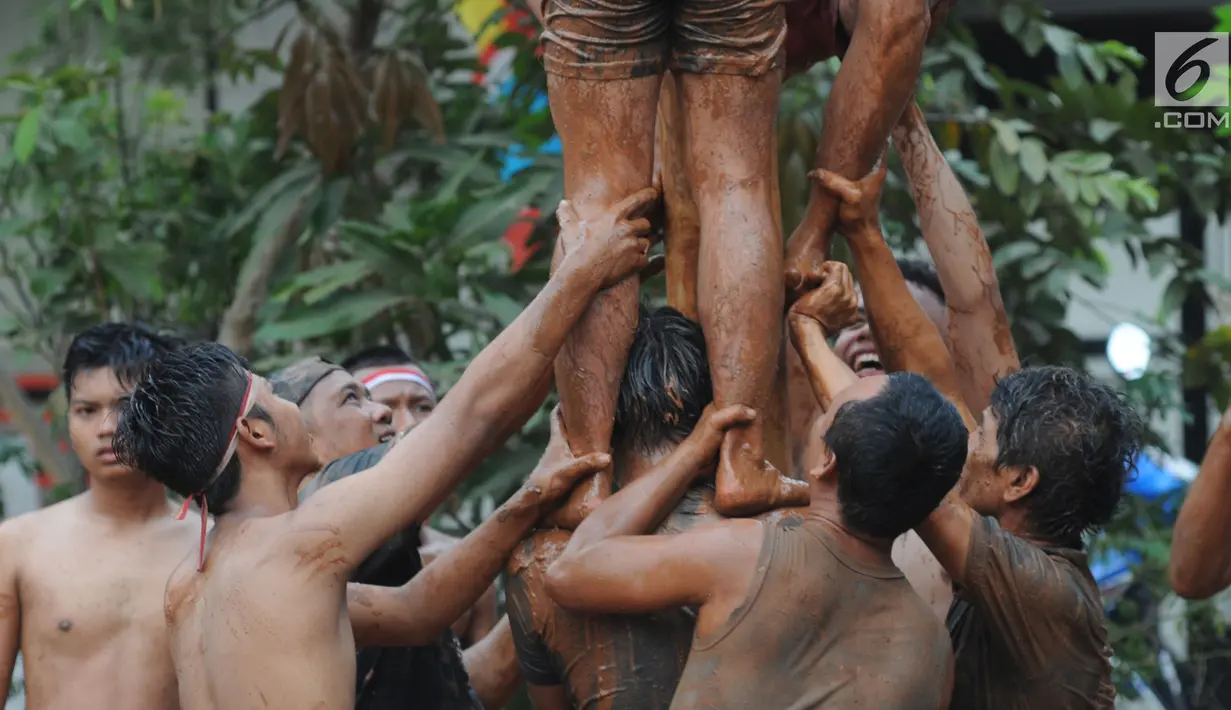 Sejumlah peserta berjibaku lumpur dan oli mengikuti lomba panjat pinang di Perumahan Griya Pamulang 2, Tangerang Selatan, Jumat (17/8). Lomba yang diselengarakan oleh Bina Remaja ini dalam rangka memeriahkan HUT Ke-73 RI. (Merdeka.com/Dwi narwoko)
