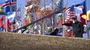 Para pekerja yang mengenakan masker berbicara dekat pajangan bendera negara-negara peserta di alun-alun terbuka di Desa Olimpiade Musim Dingin, Beijing, China, Jumat, 24 Desember 2021. Olimpiade dan Paralimpiade Musim Dingin 2022 akan diadakan mulai bulan Februari. (AP Photo/Mark Schiefelbein)