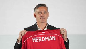 Sebagai informasi, John Herdman datang ke Indonesia dengan membawa sejumlah pengalaman sukses, terutama saat bertugas di Kanada. Dia mengantar timnas putri Kanada meraih dua medali perunggu berturut-turut dalam Olimpiade 2012 dan 2016. Tampak dalam foto, pelatih kepala tim nasional sepak bola Indonesia yang baru, John Herdman memegang jersey tim yang bertuliskan namanya saat konferensi pers di Jakarta, Selasa 13 Januari 2026. (AP Photo/Achmad Ibrahim)