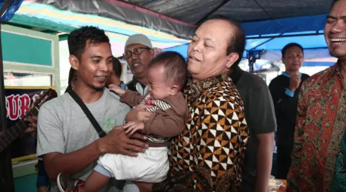 Hidayat Nur Wahid tengah menggendong seorang bayi usai makan bubur ayam.