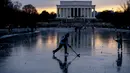 Lincoln Memorial terlihat saat bersaudara Jacek Zavora (21) dan Zach Zavora (10) dari Arlington bermain hoki di Reflecting Pool yang membeku, National Mall, Washington, Amerika Serikat, 26 Desember 2022. (AP Photo/Andrew Harnik)
