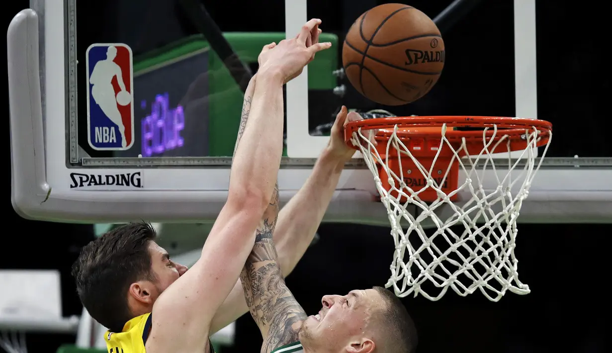 Pebasket Boston Celtics, Daniel Theis, menghadang dunk dari pebasket Indana Pacers, T.J Leaf,  pada laga NBA di TD Garden, Boston, Kamis (10/1). Celtics berhasil menang 135-108 atas Pacers. (AP/Charles Krupa)