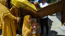 Tokoh adat dan agama mengendong bayi saat orang tua (ayah bayi) membelah kelapa pada ritual 'peutron tanoh aneuk' (turun tanah anak) di Banda Aceh, Aceh, Senin (15/7/2019). Ritual turun tanah anak dilaksanakan pada saat bayi berusia 44 hari. (CHAIDEER MAHYUDDIN / AFP)