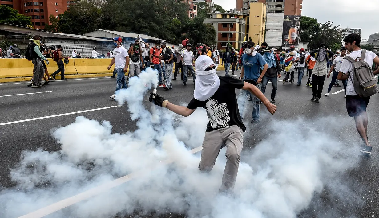 Demonstran melempar gas air mata yang telah ditembakkan polisi saat aksi menentang Presiden Venezuela Nicolas Maduro di Caracas, kamis (20/4). Tiga orang dikabarkan tewas dalam aksi demonstrasi tersebut.  (AFP PHOTO/ Juan BARRETO)