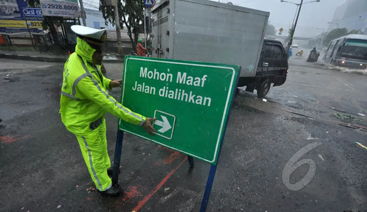 Seorang petugas memasang papan pengalihan jalan akibat banjir yang menggenangi jalan Gunung Sahari, Jakarta, Senin (9/2/2015).  (Liputan6.com/Faizal Fanani)