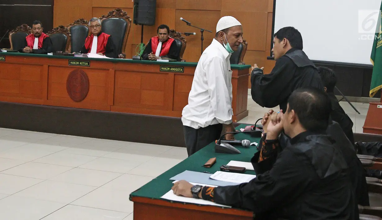 Terdakwa kasus penembakan dr Letty Sultri, dr Helmi berdiskusi dengan kuasa hukumnya saat sidang mendengarkan dakwaan di PN Jakarta Timur, Kamis (29/3). Helmi didakwa menembak istrinya sebanyak enam kali di bagian badan. (Liputan6.com/Herman Zakharia)