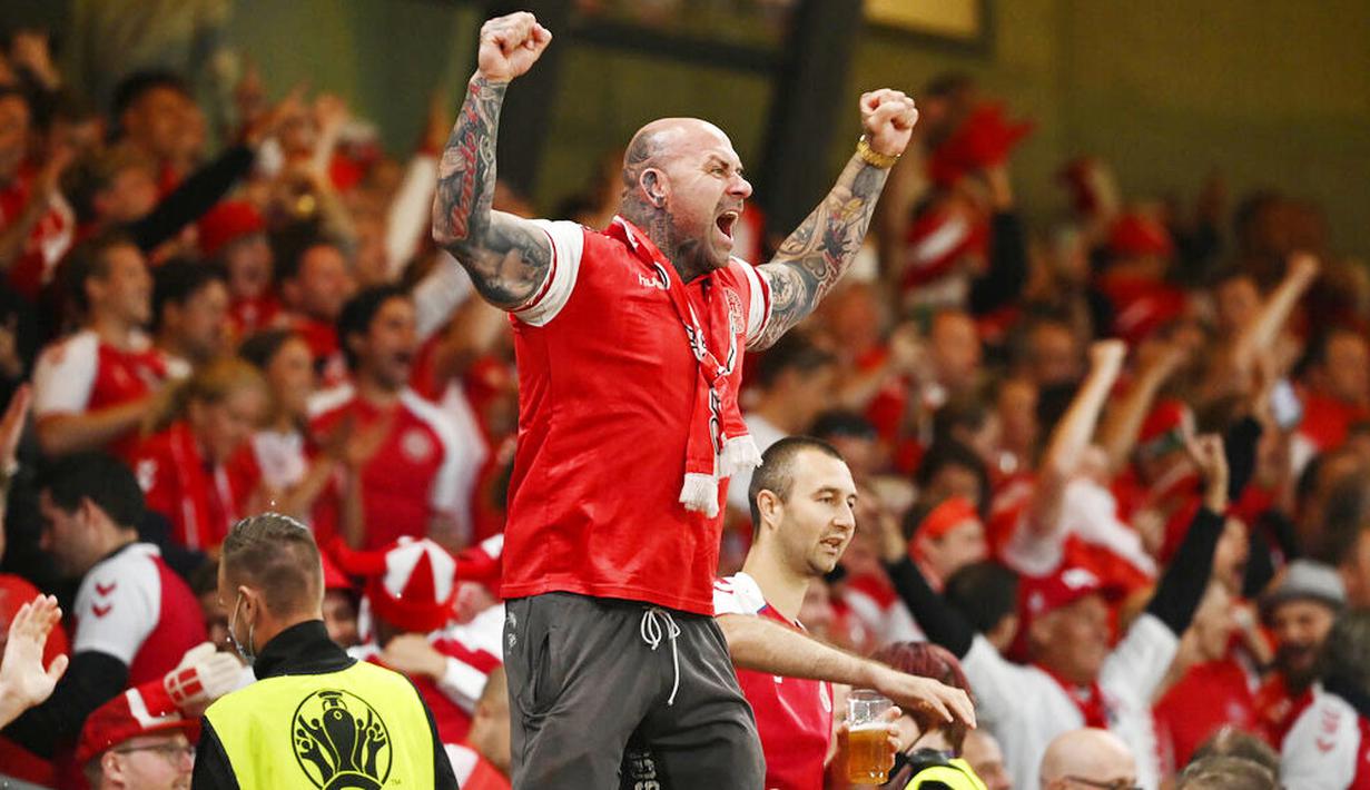 Sorang suporter Denmark dengan menggebu-gebu merayakan kesuksesan Tim Dinamit yang secara dramatis lolos ke babak 16 besar Euro 2020. (Jonathan Nackstrand/Pool via AP)