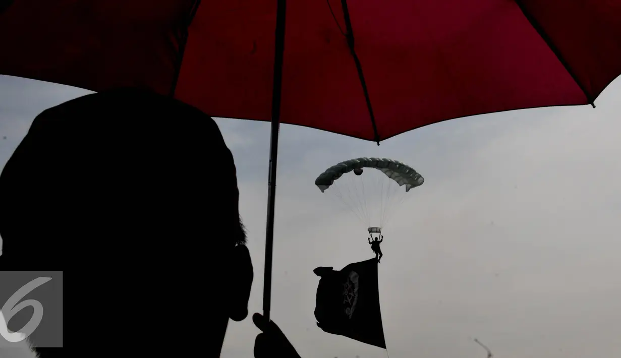 Seorang warga menonton aksi para prajurit aksi terjun Payung saat Peringatan HUT TNI AU ke - 70 di Lanud Halim Perdanakusuma, Jakarta, (9/4). Sejumlah atraksi ditampilkan oleh prajurit TNI AU. (Liputan6.com/Johan Tallo)