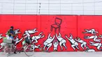 Warga berjualan di depan mural bernuansa politik di Penjaringan, Jakarta, Minggu (7/8). Jelang Pilkada 2017, sejumlah lokasi di Jakarta dihiasi mural politik. (Liputan6.com/Angga Yuniar)