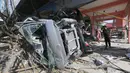 Warga mengecek rumah dan mobil yang hancur setelah gempa dan tsunami di pantai Talise di Palu, Sulawesi Tengah (1/10). Gempa berkekuatan 7,4 Magnitudo disusul tsunami melanda Palu dan Donggala pada 28 September 2018. (AP Photo/Tatan Syuflana)
