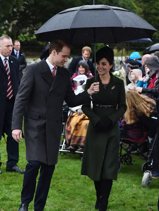 Kate Middleton berjalan bersama suaminya, Pangeran William menggunakan payung usai menghadiri Misa Natal yang digelar secara tradisional bersama keluarga kerajaan di Gereja St. Mary Magdalene di Sandringham, Inggris, (25/12/2015). (AFP/BEN STANSALL)