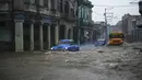 Mobil dan bus tua Amerika Serikat melewati jalan yang banjir di Havana, Kuba, 30 Juni 2021. Hujan deras dan selokan yang tidak berfungsi menyebabkan banjir di jalan-jalan di Havana. (YAMIL LAGE/AFP)
