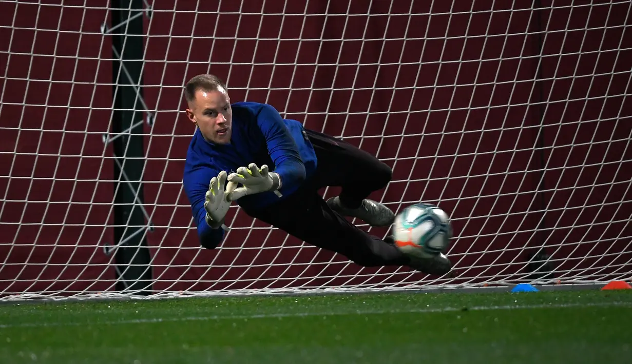 Kiper Barcelona, Marc-Andre Ter Stegen berusaha menangkap bola saat mengikuti sesi latihan tim di Joan Gamper Sports City di Sant Joan Despi (17/12/2019). Barcelona akan bertanding melawan Real Madrid dalam laga El Clasico di Camp Nou. (AFP/Lluis Gene)