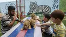 Anak-anak Palestina didampingi seorang pekerja bermain dengan tiga bayi singa yang baru lahir di sebuah kebun binatang di Rafah, Jalur Gaza (8/9/2019). Kehadiran tiga bayi singa ini menambah koleksi satwa sebuah kebun binatang tersebut. (AFP Photo/Said Khatib)