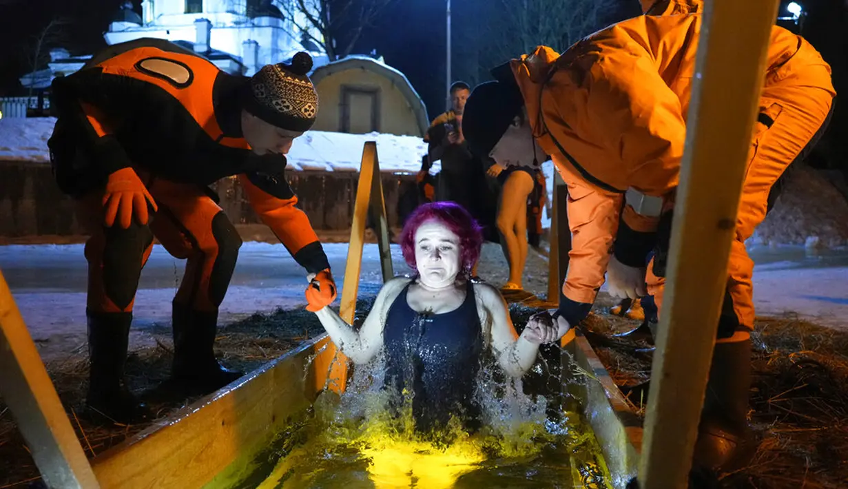 Petugas penyelamat membantu penganut Kristen Ortodoks Rusia berendam dalam air es saat perayaan Epiphany tradisional di St. Petersburg, Rusia, 19 Januari 2022. Ribuan penganut Kristen Ortodoks Rusia merayakan Epiphany dengan membenamkan diri dalam air dingin. (AP Photo/Dmitri Lovetsky)