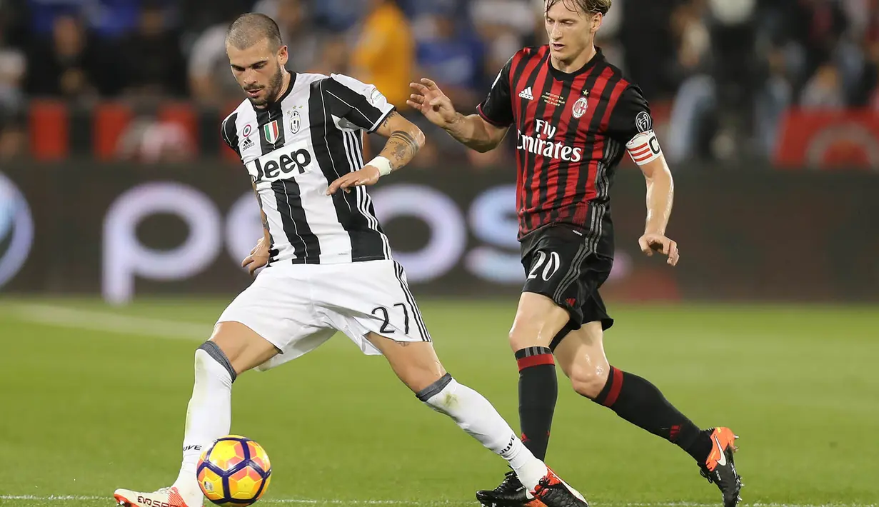 Gelandang Juventus, Stefano Sturaro, berusaha melewati bek AC Milan, Ignazio Abate, pada laga Piala Super Italia 2016. Juventus lebih menguasai jalannya laga dengan penguasaan bola 52 persen. (AFP/Karim Jaafar)
