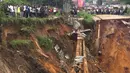 Warga melihat jalan ambruk oleh tanah longsor yang disebabkan hujan lebat melanda distrik Lemba, Kinshasa di Republik Demokratik Kongo pada Selasa (26/11/2019). Bencana tanah longsor ini juga telah melumpuhkan aktivitas warga dan lalu lintas. (AFP/Ange Kasongo)