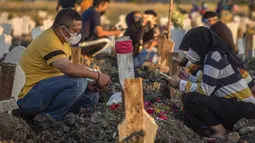 Keluarga berdoa untuk kerabat mereka di lokasi pemakaman korban virus corona COVID-19 di TPU Keputih, Surabaya, Jawa Timur, Sabtu (17/7/2021). Di Kota Surabaya terdapat dua tempat lahan pemakaman khusus blok COVID-19 yakni TPU Keputih dan TPU Babat Jerawat. (JUNI KRISWANTO/AFP)