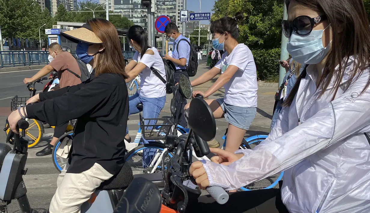 Para komuter yang mengenakan masker menunggu di persimpangan kawasan pusat bisnis di Beijing, China, Selasa (31/5/2022). Penguncian COVID-19 di Shanghai telah mencekik ekonomi nasional dan sebagian besar mengurung jutaan orang di rumah mereka. (AP Photo/Mark Schiefelbein)