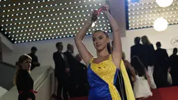 Seorang pengunjuk rasa yang mengenakan gaun berwarna bendera Ukraina melakukan demonstrasi dramatis di karpet merah Festival Film Cannes. (AP Photo/Daniel Cole)