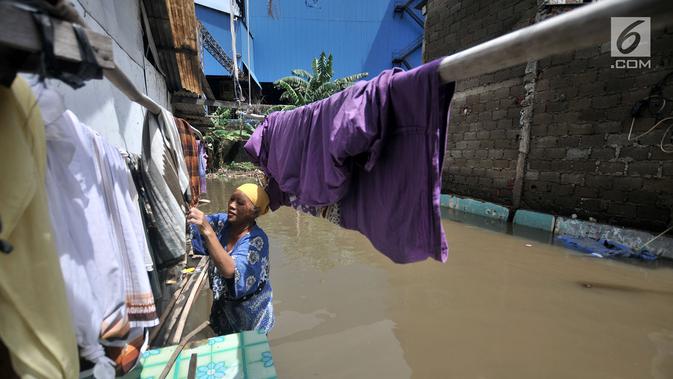 Warga menjemur pakaian saat banjir menggenangi kawasan Rawa Terate, Cakung Jakarta, Rabu (30/1). Ratusan rumah di RT 016/004 dan RT 010/005 Kelurahan Rawa Terate, terendam banjir sejak dini hari. (merdeka.com/Iqbal S. Nugroho)