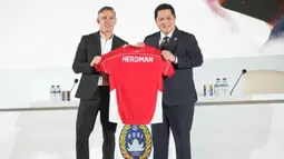 Pengangkatan Herdman sebelumnya telah lebih dulu diumumkan melalui media sosial federasi pada 3 Januari 2026 silam. Tampak dalam foto, Pelatih kepala baru tim nasional sepak bola Indonesia, John Herdman (kiri), dan Ketua Persatuan Sepak Bola Seluruh Indonesia (PSSI), Erick Thohir memegang jersey saat konferensi pers di Jakarta, Selasa 13 Januari 2026. (AP Photo/Achmad Ibrahim)