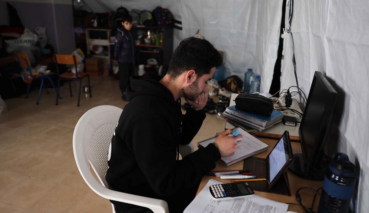 Upaya ini merupakan langkah darurat untuk memastikan hak pendidikan anak-anak tetap terpenuhi di tengah krisis keamanan dan kemanusiaan yang sedang berlangsung di Lebanon. Tampak dalam foto, seorang pria Lebanon yang mengungsi melanjutkan studinya secara daring di sebuah sekolah negeri yang diubah menjadi tempat penampungan, di kota Dekwaneh, utara Beirut pada Rabu 25 Maret 2026. (Anwar AMRO/AFP)