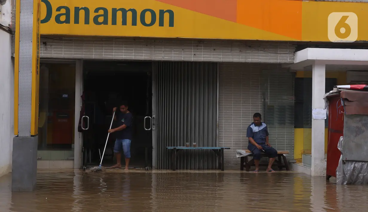 Pekerja membersihkan sebuah bank saat banjir merendam di Kawasan Bendungan Hilir (Benhil), Jakarta Pusat,  Selasa (25/2/2020). Salah satu wilayah terdampak banjir yakni kawasan Benhil hingga membuat akses jalan untuk sementara terputus.  (Liputan6.com/Angga Yuniar)