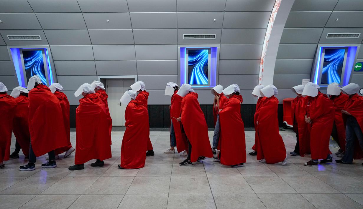 Pengunjuk rasa yang mendukung hak-hak perempuan berpakaian seperti karakter dari serial TV "The Handmaid's Tale" saat melakukan perjalanan untuk memprotes rencana pemerintah baru Perdana Menteri Benjamin Netanyahu untuk merombak sistem peradilan di sebuah stasiun kereta api di Yerusalem, Israel, 1 Maret 2023. Mengacu pada fenomena yang berkembang, harian Inggris The Guardian menggambarkan penampilan para pelayan sebagai salah satu simbol paling kuat dari protes feminis kontemporer. (AP Photo/Ohad Zwigenberg)
