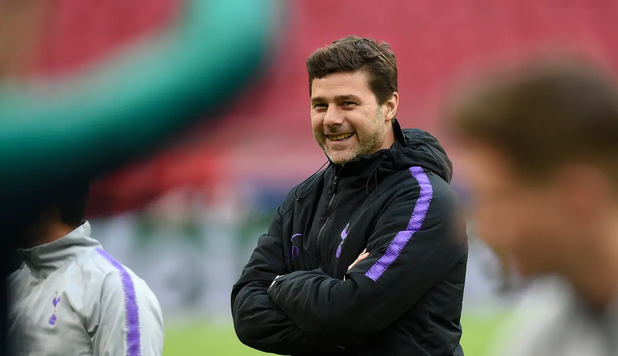 Pelatih Tottenham Hotspur, Mauricio Pochettino tersenyum saat melihat pemainnya berlatih selama sesi latihan tim di Amsterdam, Belanda  (7/5/2019). Tottenham akan bertanding melawan Ajax Amsterdam pada leg kedua babak semifinal Liga Champions di Johan Cruijff Arena. (AFP Photo/Emmanuel Dunand)