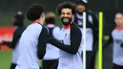 Striker Liverpool, Mohamed Salah bercanda dengan rekannya saat sesi latihan di AXA Training Centre, Liverpool (20/2/2023) menjelang menghadapi Real Madrid dalam laga leg pertama babak 16 besar Liga Champions 2022/2023. Mohamed Salah berpeluang membuat rekor sebagai top skor Liverpool di pentas Eropa jika mampu mencetak minimal satu gol ke gawang Real Madrid dalam laga dua leg. Saat ini Mohamed Salah duduk sejajar dengan legenda Liverpool, Steven Gerrard yang sama-sama mengemas total 41 gol di kancah Eropa. (AFP/Lindsey Parnaby)