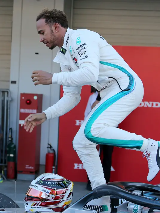Pembalap Mercedes, Lewis Hamilton turun dari mobilnya usai meraih kemenangan Formula Satu (F1) Grand Pix Jepang di Sirkuit Suzuka, Jepang (7/10). Pembalap Red Bull Racing Max Verstappen meraih posisi ketiga. (AP Photo/Toru Takahashi)