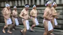 Penganut Shinto berlari saat melakukan pemanasan sebelum mandi dengan air dingin di Kuil Teppozu Inari, Tokyo, Jepang, 8 Januari 2023. Ritual Tahun Baru ini dilakukan untuk memurnikan jiwa dan raga. (Philip FONG/AFP)