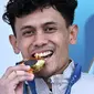 Atlet panjat tebing Indonesia, Veddriq Leonardo menggigit medali emas saat di atas podium cabang olahraga panjat tebing nomor speed Olimpiade Paris 2024 di Le Bourget Sport Climbing Venue, Paris, Prancis, Kamis (08/08/2024). (AFP/Jonathan Nackstrand)