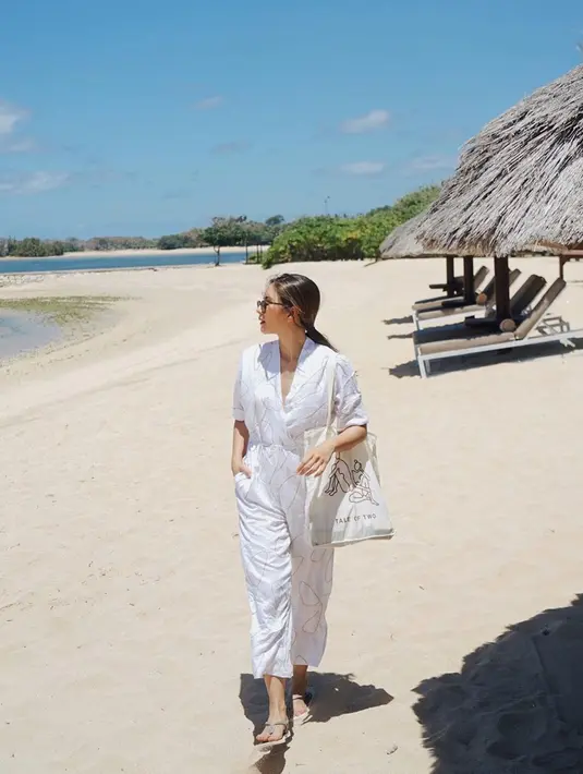 Jumpsuit putih berwarna putih yang digunakan oleh Mila saat bersantai di pantai ini juga terlihat simpel. Dirinya tampak memadukan penampilan santainya dengan sebuah sandal jepit serta tote bag. (Liputan6.com/IG/@jscmila)