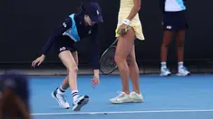 Seorang ball girl berusaha menangkap seekor serangga yang memasuki lapangan ketika laga Australia Open 2024 antara petenis Inggris, Emma Raducanu melawan petenis Amerika Serikat di Melbourne Park, Melbourne, Australia, Selasa (16/01/2024). (AFP/David Gray)