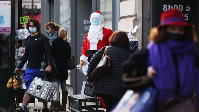 Warga berjalan melewati seseorang yang berpakaian Sinterklas di luar sebuah pasar swalayan di Paris, Prancis, 25 November 2020. Kebijakan karantina wilayah (lockdown) virus corona COVID-19 secara nasional dapat dicabut pada 15 Desember jika kondisi kesehatan di negara itu membaik. (Xinhua/Gao Jing)