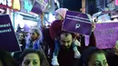 Seorang pria sambil menggendong anaknya ikut ambil bagian dalam demonstrasi di Istanbul, Sabtu (19/11). Massa menentang RUU yang memberikan pengampunan kepada pria pemerkosa perempuan di bawah umur jika pelaku menikahi korban. (YASIN AKGUL/AFP)