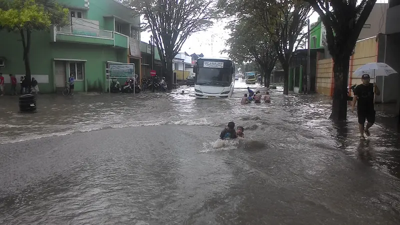 Jalan raya yang tergenang banjir menjadi area berenang dan area bermain anak-anak di Garut, Jawa Barat