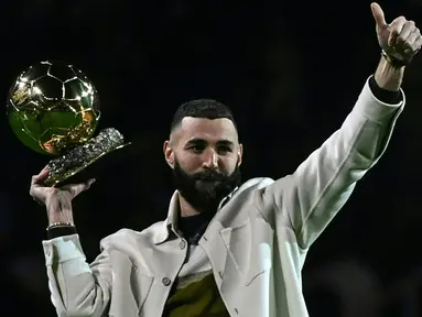 Pemain Real Madrid Karim Benzema berpose di lapangan dengan trofi Ballon d'Or miliknya pada babak pertama pertandingan sepak bola L1 Prancis antara Olympique Lyonnais (OL) dan OGC Nice di Stadion Groupama, Decines-Charpieu, Prancis, 11 November 2022. Karim Benzema memamerkan trofi Ballon d'Or kepada para fans Olympique Lyon yang notabenenya adalah kota kelahirannya. (OLIVIER CHASSIGNOLE/AFP)