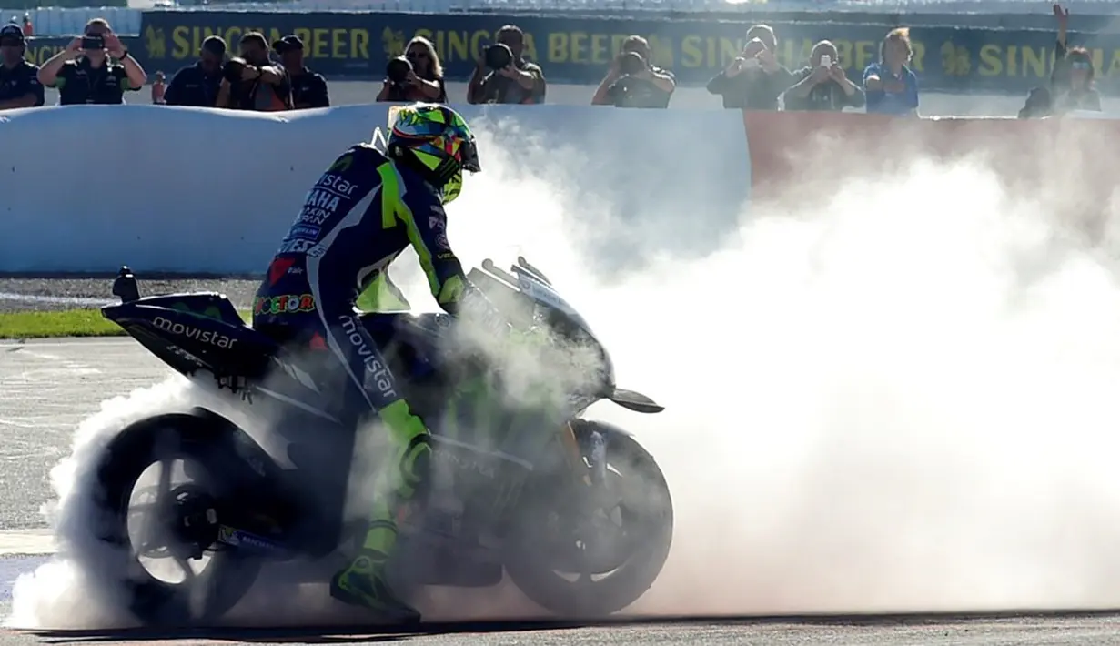 Pebalap Movistar Yamaha, Valentino Rossi, melakukan burn out setelah finis keempat dalam balapan MotoGP Valencia di Sirkuit Ricardo Tormo, Minggu (13/11/2016). (AFP/Jose Jordan)