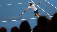 Petenis Swiss, Roger Federer berusaha mengembalikan bola ke arah Taylor Fritz dari AS dalam babak 32 besar Australia Terbuka di Melbourne, Jumat (18/1). Federer melaju mulus ke babak 16 besar setelah menang tiga set langsung 6-2 7-5 6-2. (AP/Kin Cheung)